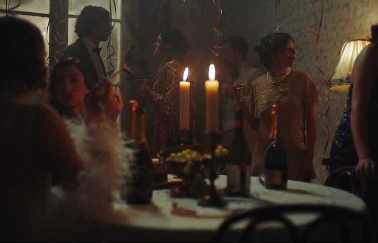 People in an indoor environment such as a table with wine and candles wearing fashionable and formal clothes talking to each other at a party