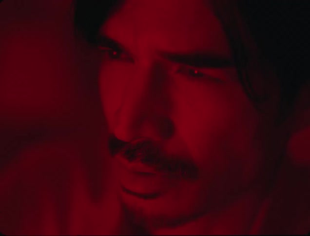 Portrait of a man with a red light on his face in a dark indoor environment