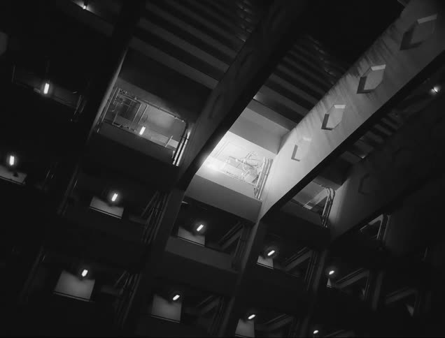 An interior light shines through windows in a tall building