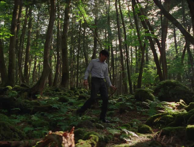 Man wearing office clothes walks over the uneven ground in the woods on a sunny day