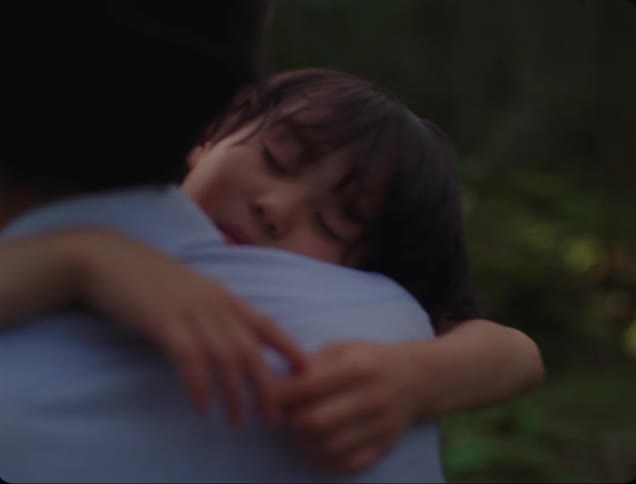 Man carries a sleepy girl through the woods