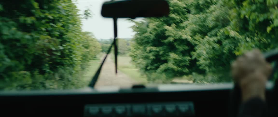 Male driver steers his vehicle along a narrow dirt road with the windshield wipers on
