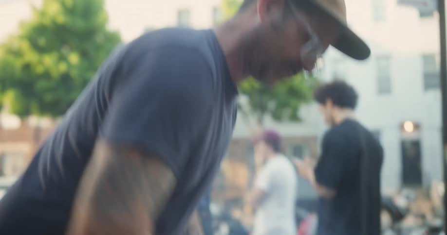 Man grills hot dogs on a parking lot near a busy street during a sunny day