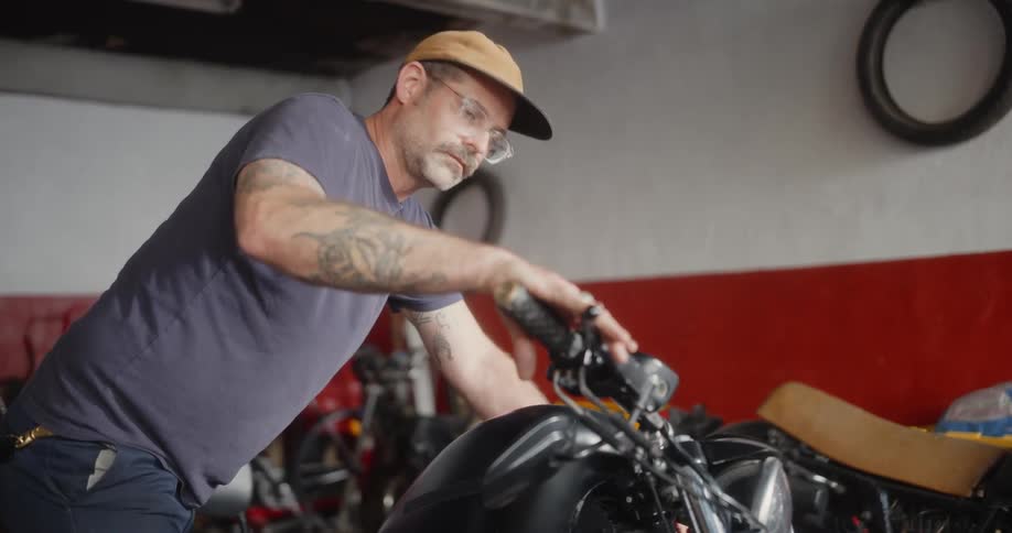 A male mechanic works on a motorcycle in a repair shop