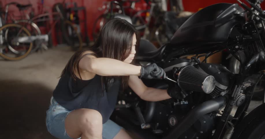 A female mechanic repairs a motorcycle inside a shop