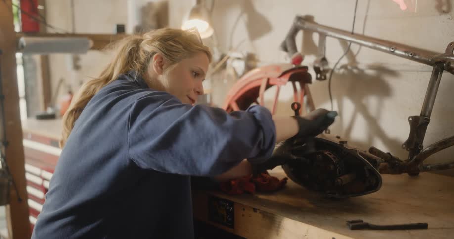Female mechanic cleans a vehicle part with a brush
