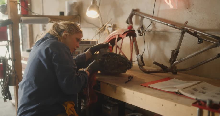 A mechanic in a workshop working on a motorcycle engine placed on a workbench