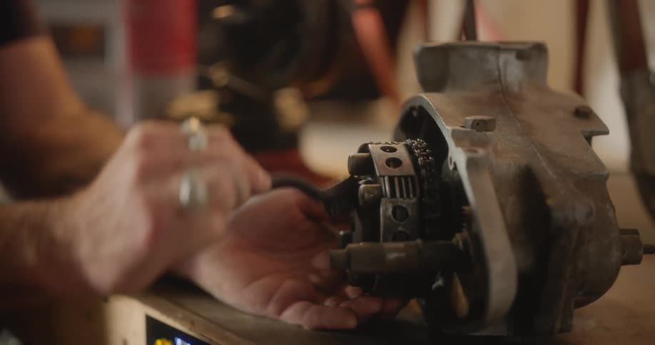 A man cleans a motor with a brush