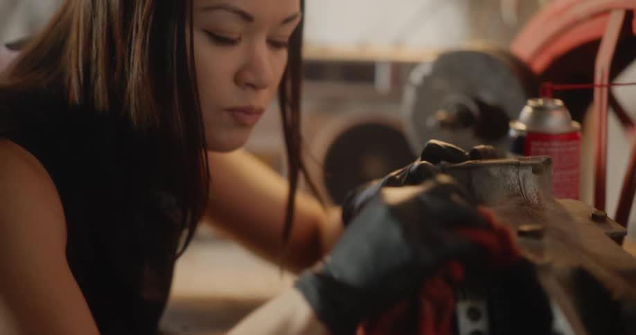Woman cleans a piece of machinery while in the garage