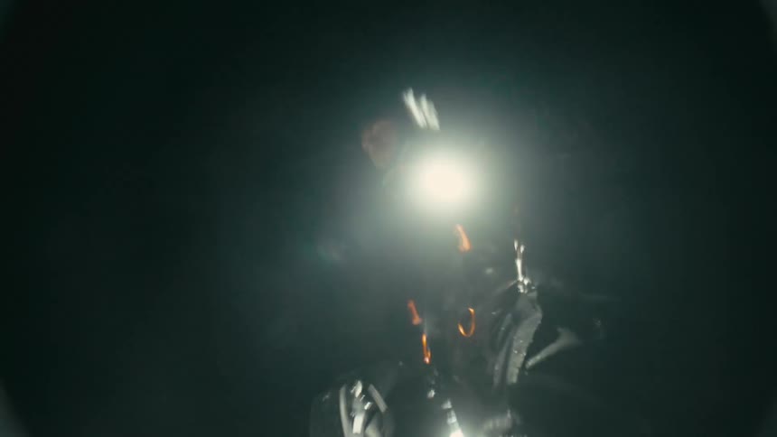 View of moving water and a person in the background with a flashlight on their head in an outdoor setting at night