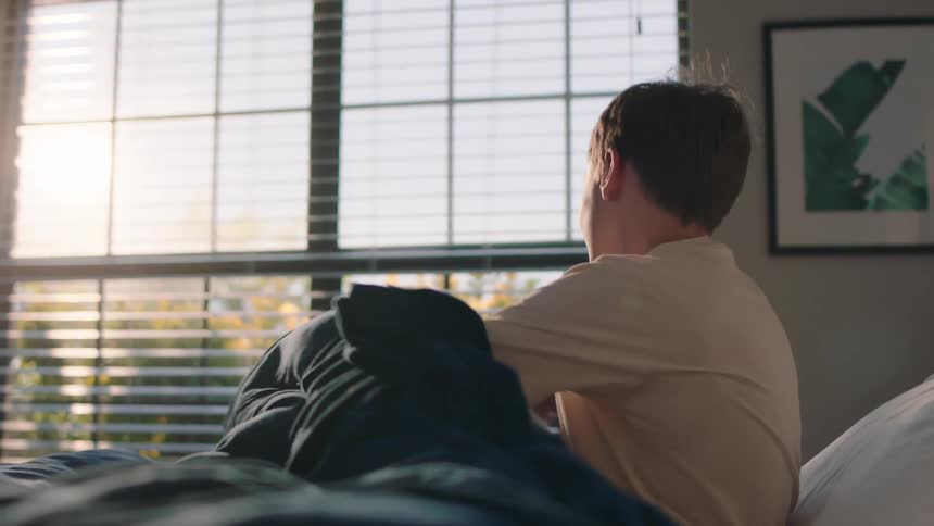 Boy sitting on bed stretching