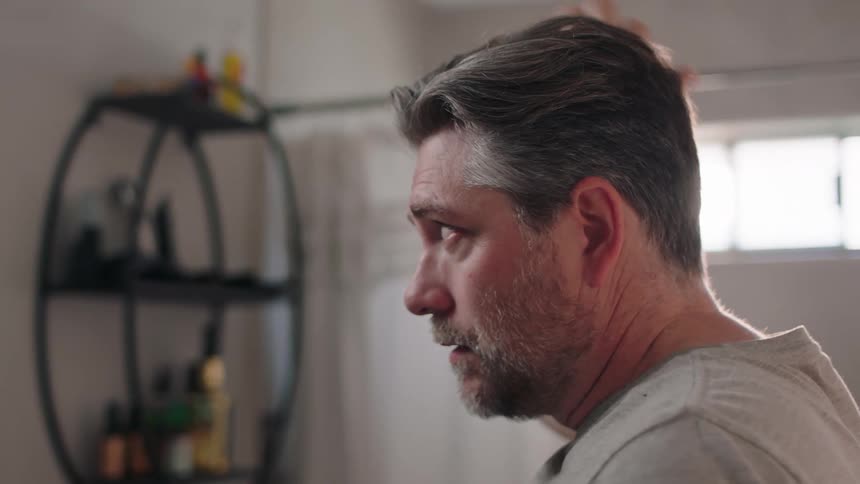 Man in front of a mirror fixing his hair with his hands