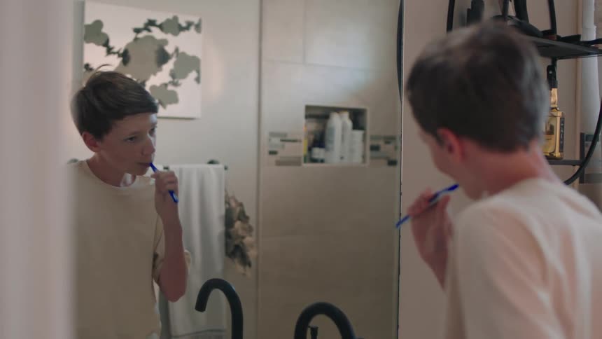 Boy in front of the mirror brushing his teeth in the bathroom