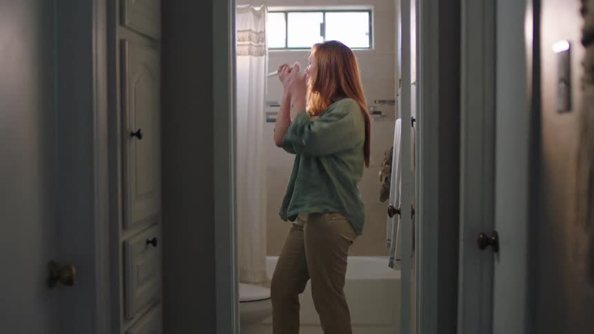 A woman walks into the bathroom and puts on makeup