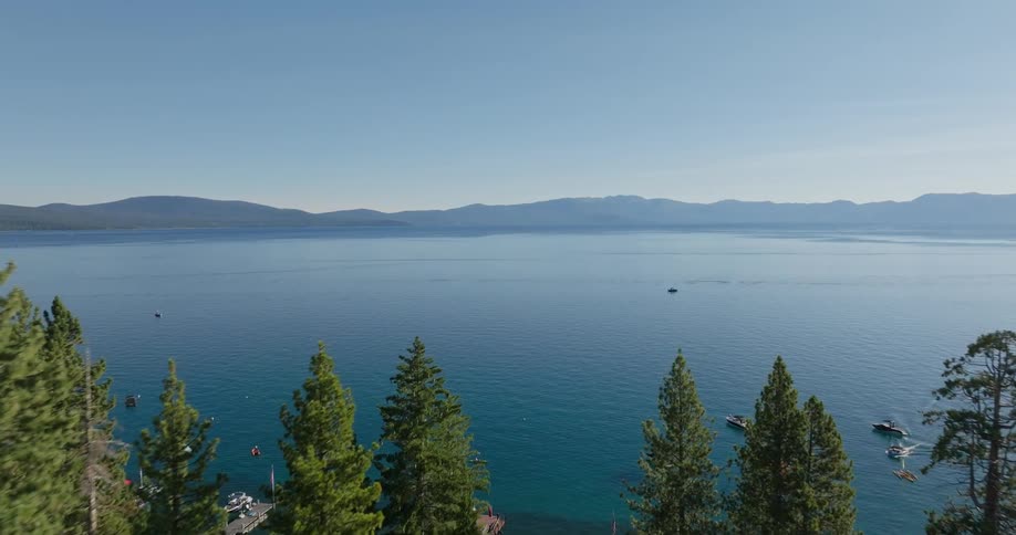 Aerial landscape of conifers in the foreground next to a lake surrounded by mountains