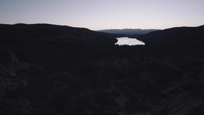 A twilight scene over rugged hills with a lake nestled between them