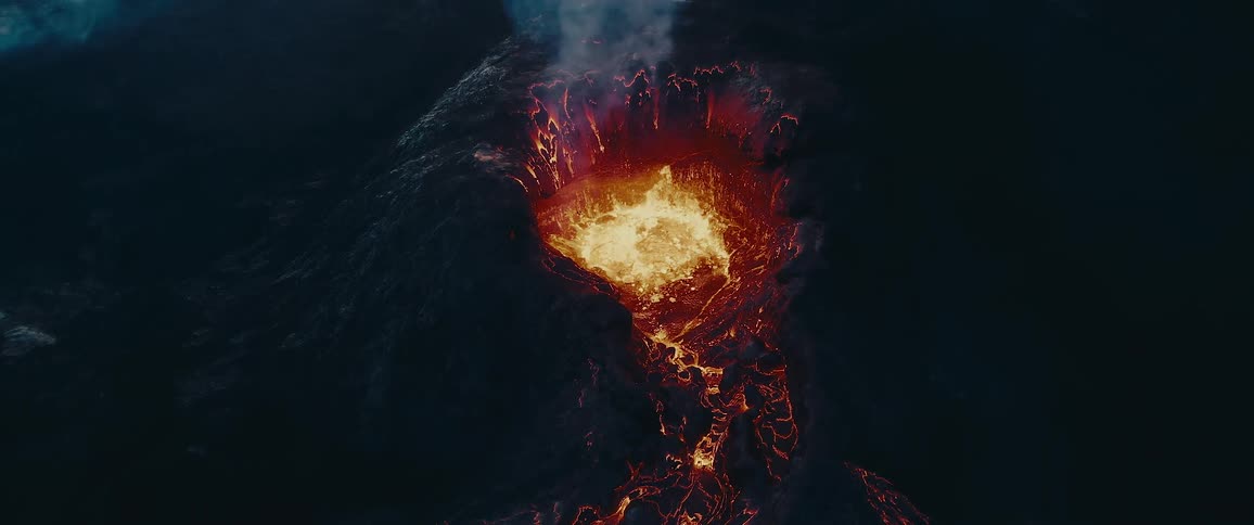 An aerial view of a volcanic eruption with lava flowing from the crater