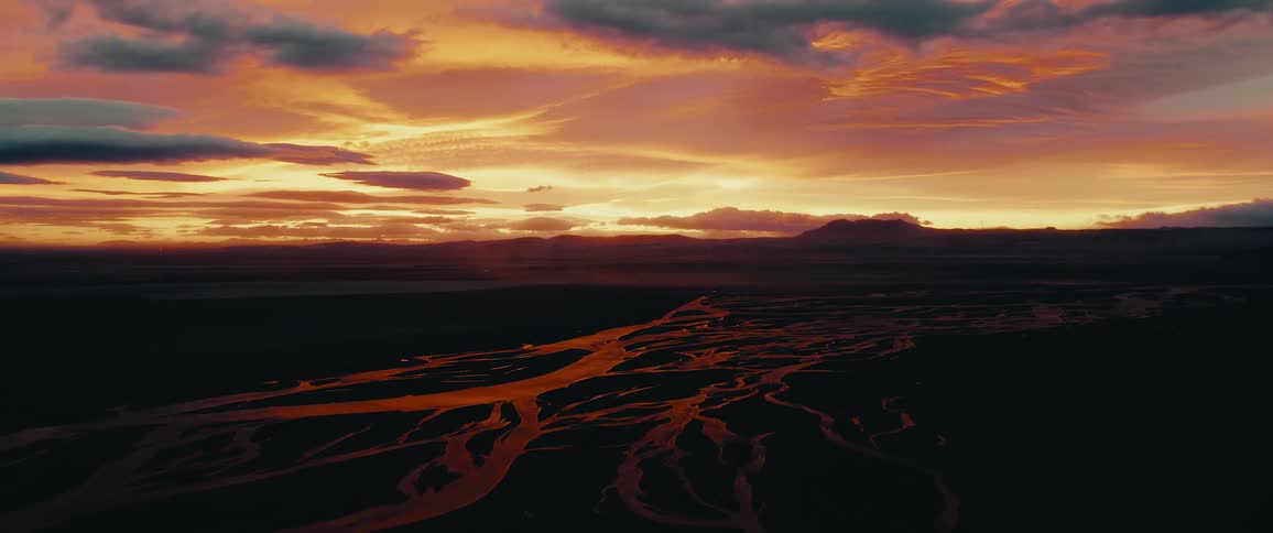 A serene sunset over a vast landscape with meandering rivers reflecting the remaining light