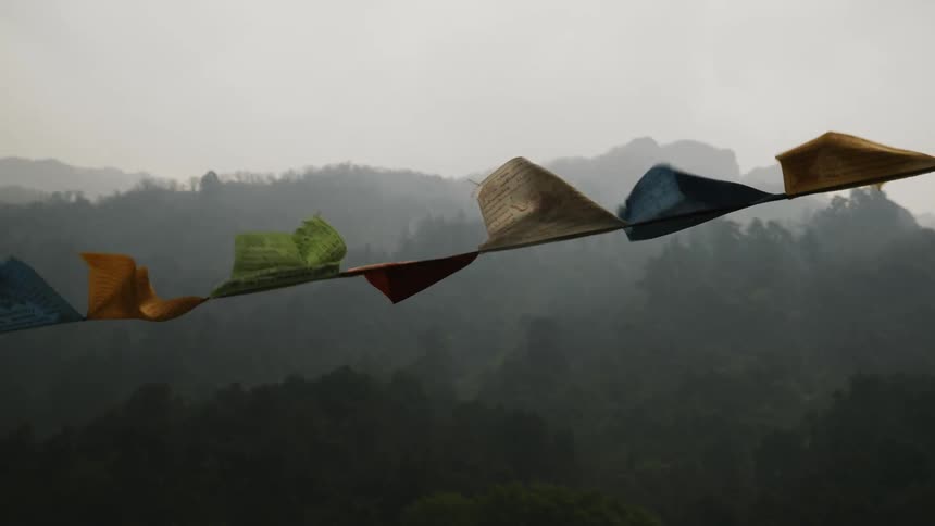 Multicolored pennant flags are blowing in the wind near a mountain range