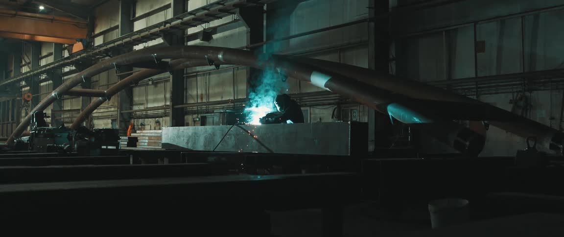 Person using a welding tool that produces smoke and sparks inside a factory