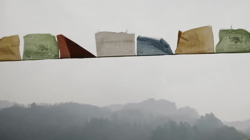Strings of colorful tissue paper flying due to the force of the wind and in the background mountains with trees and trees around them
