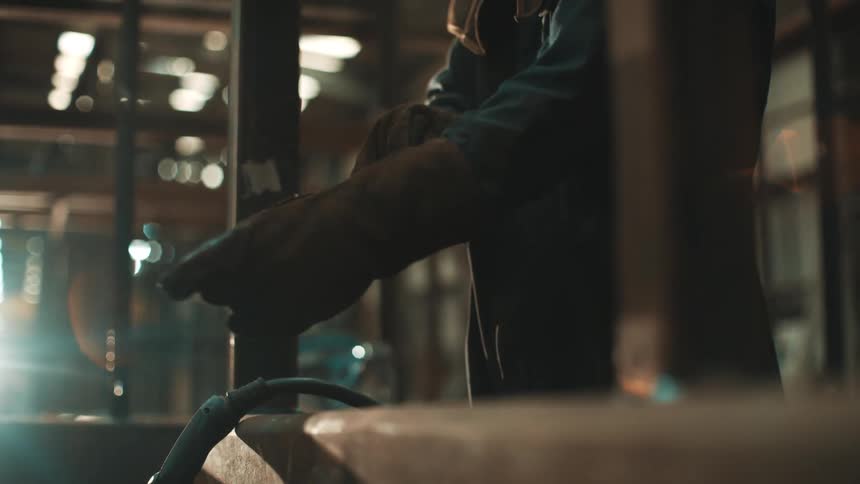 A close up of hands wearing heavy leather gloves for metalworking
