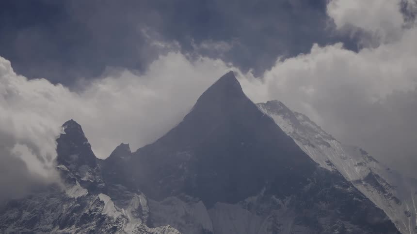 A snowy mountain peak surrounded by clouds