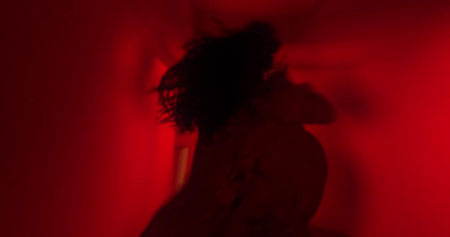 Woman running desperately through dark corridors with eerily flashing red lights