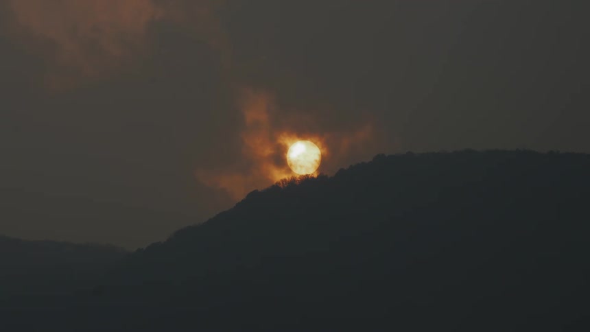 The sun sets behind a mountain
