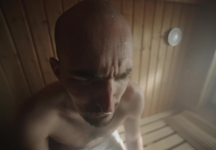 A man sits in a sauna breathing slowly relaxing