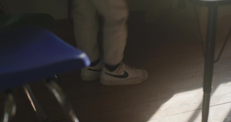 Legs of a person wearing white sneakers indoors