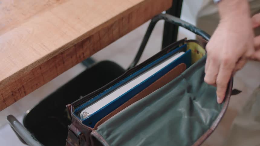 Documents being placed inside a leather bag
