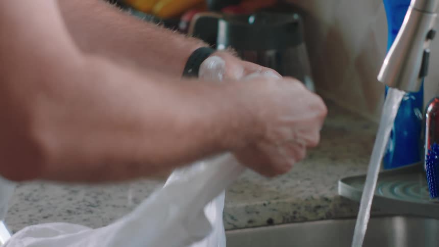 A person cleaning a white shirt on the kitchen sink