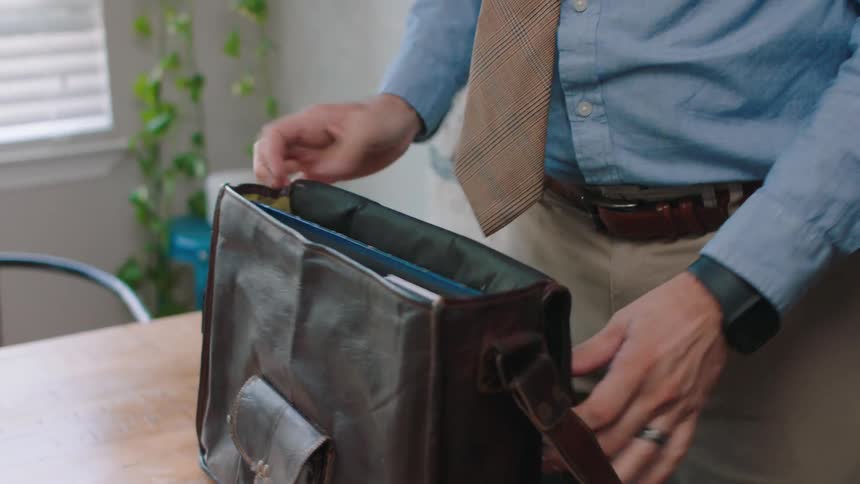 Man placing a leather backpack on the table and storing documents