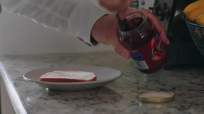 A man toasts bread and puts jam on it