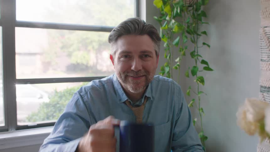 Bearded man drinking a cup of coffee and smiling