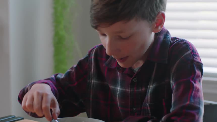 Boy sitting at the table with a bowl and eating