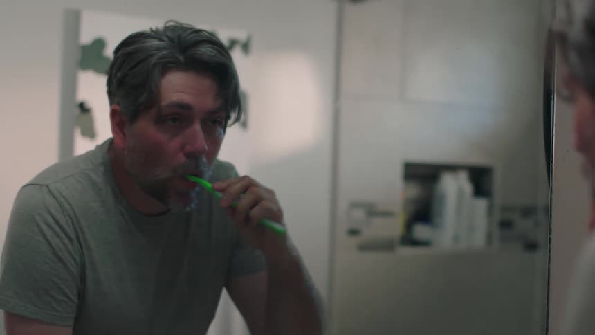 A man brushing his teeth in the bathroom at home
