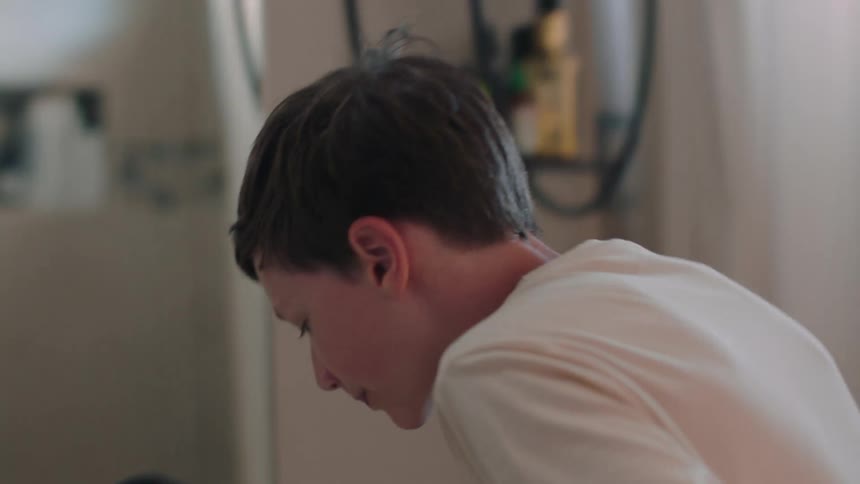 A teenage boy brushing his teeth in the bathroom at morning