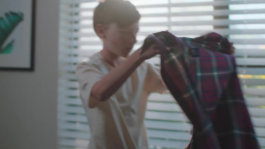 A boy picks up his sweater