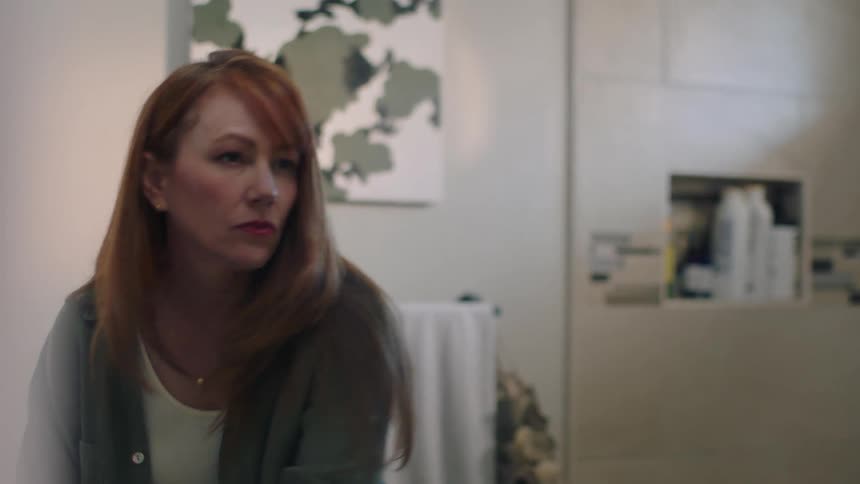 Woman in the bathroom putting on lipstick and combing her hair in front of the mirror