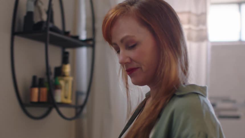 A woman stands in the bathroom and brushes her hair