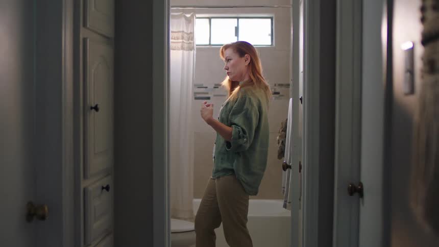 A woman combing her hair in the bahtroom at home