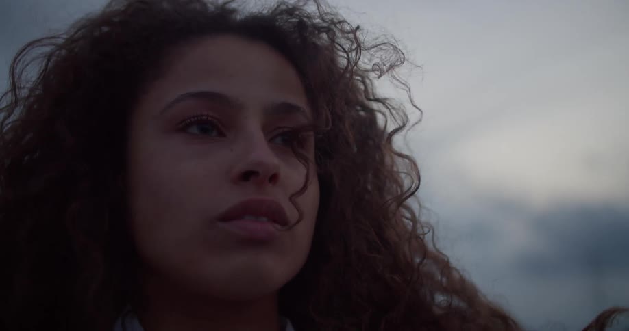 Portrait of a woman with curly hair and a sad facial expression