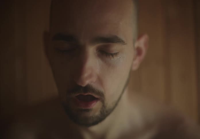 Portrait of a sweaty man inside a sauna with a strange facial expression