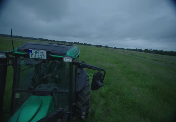 A tractor is driving through the grass
