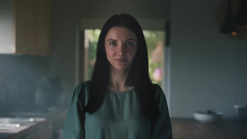 A woman standing in her kitchen determined and grinning