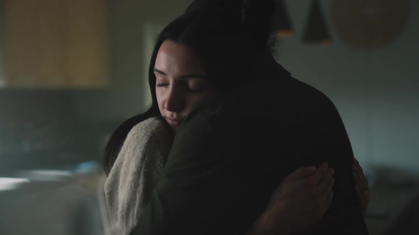 A woman rests her head on a mans shoulder as they hug