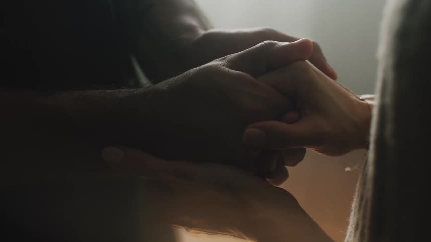 Two people are holding hands while sitting indoors