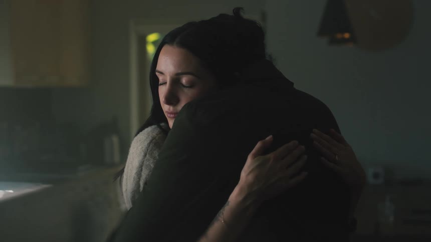 A woman hugs her husband and picks up her young son